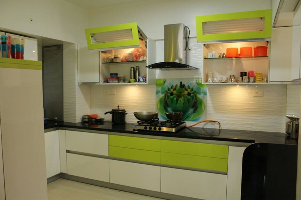 Green color L-shaped modular kitchen with sleek cabinets and modern appliances