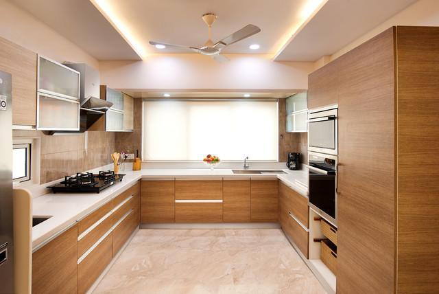 Modern L-shaped kitchen with wood cabinets, white counters, gas cooktop, built-in oven, and a ceiling fan.