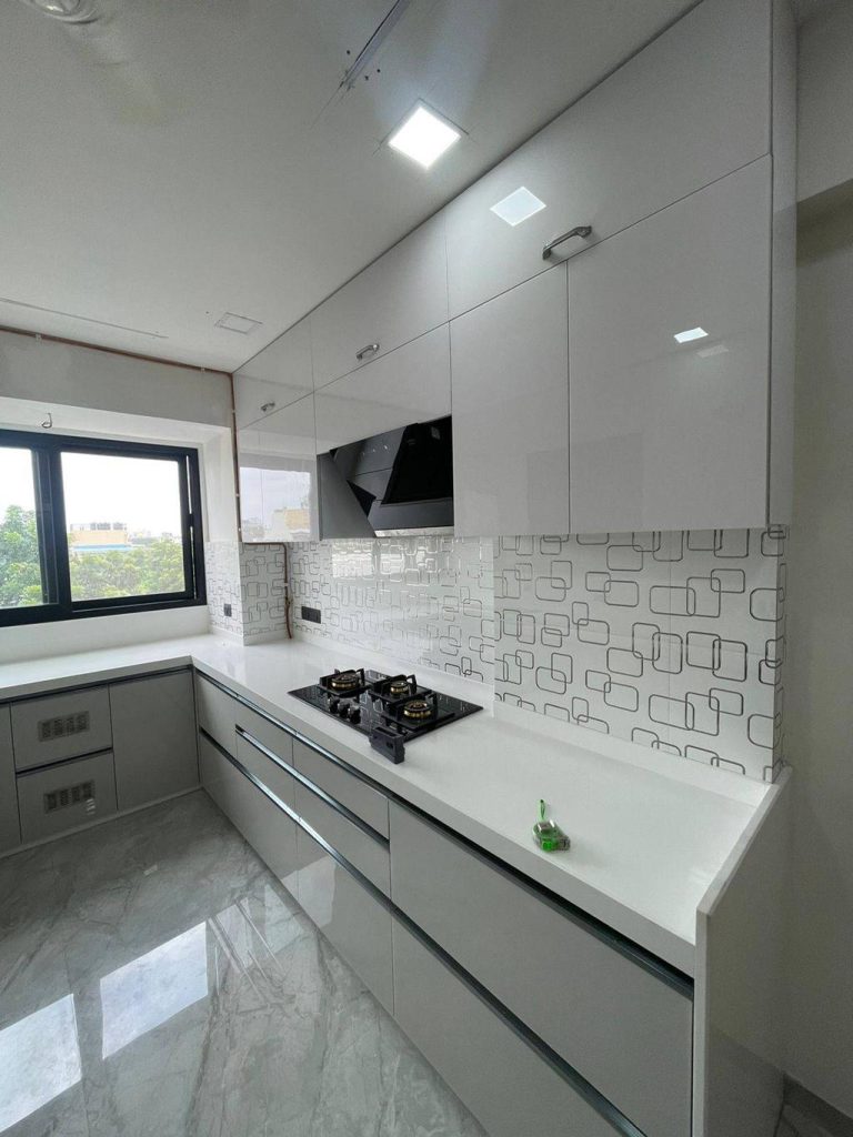 Premium modular kitchen with modern white cabinets and smart storage by SLE Pune.
